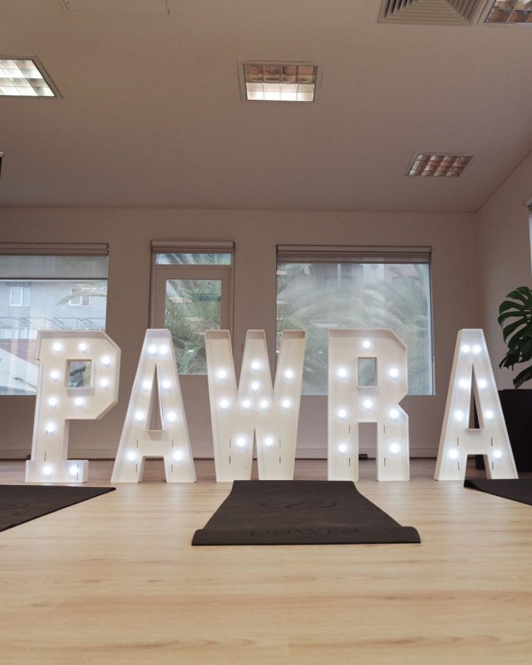 Illuminated Pawra marquee letters on the floor of the yoga studio with mats laid out